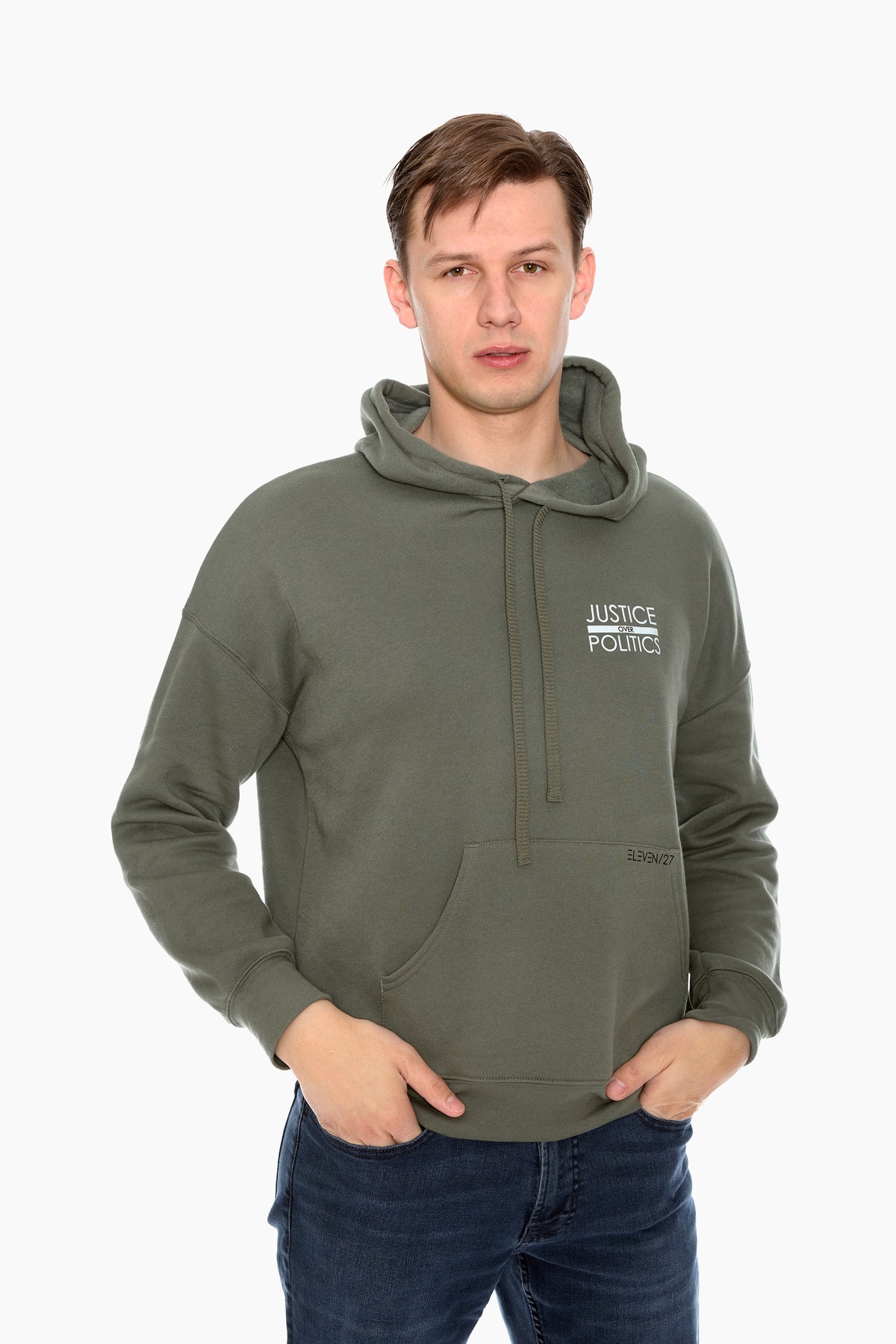 A male model wearing a green full-length hoodie with a "Justice Over Politics" graphic on the front and a logo on the back, featuring a front kangaroo pocket and drop shoulder design.
