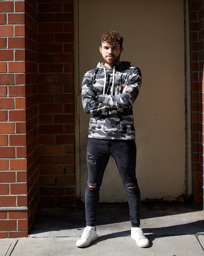 Photo of model wearing full length camo hoodie and distressed jeans