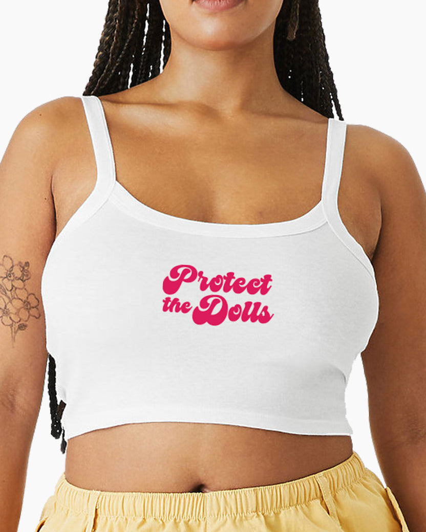 Woman wearing a white Eleven27 tank top with 'Protect the Dolls' text in pink on a white background