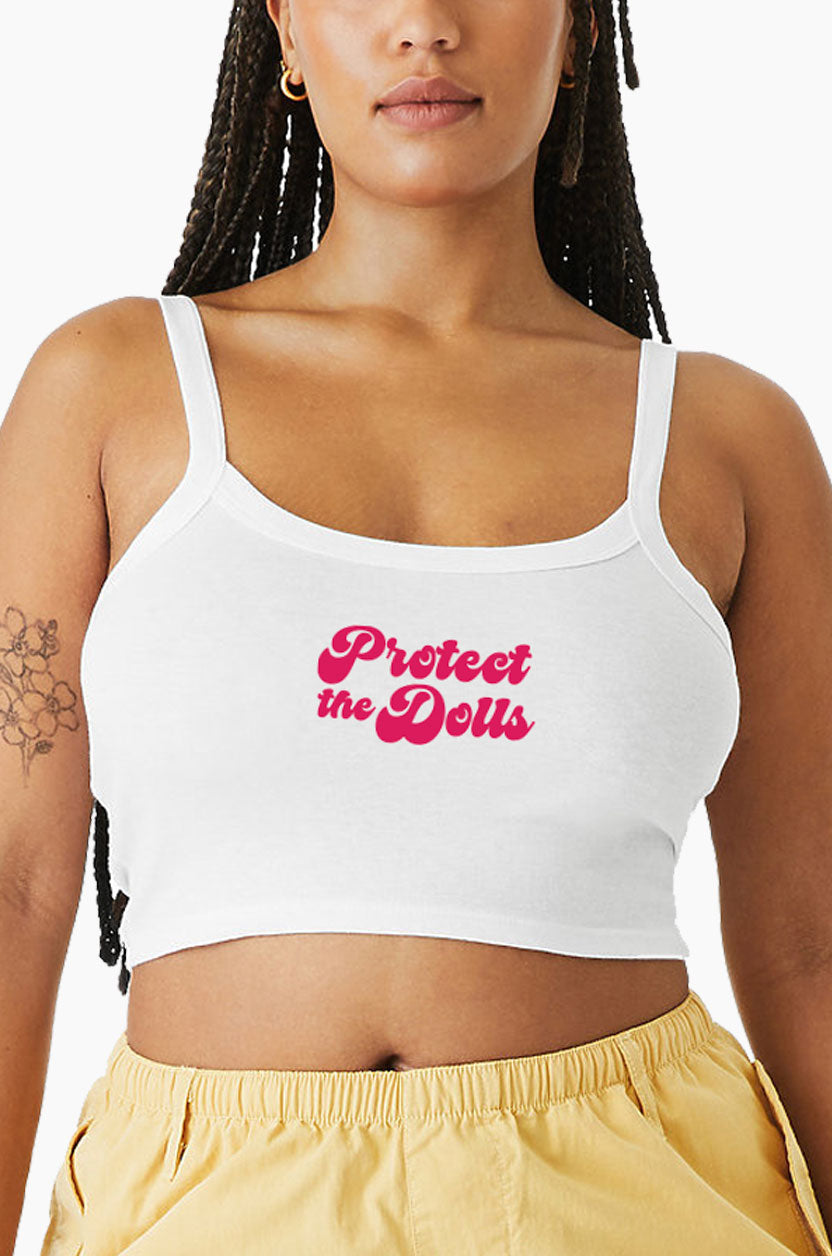 Woman wearing a white Eleven27 tank top with 'Protect the Dolls' text in pink on a white background