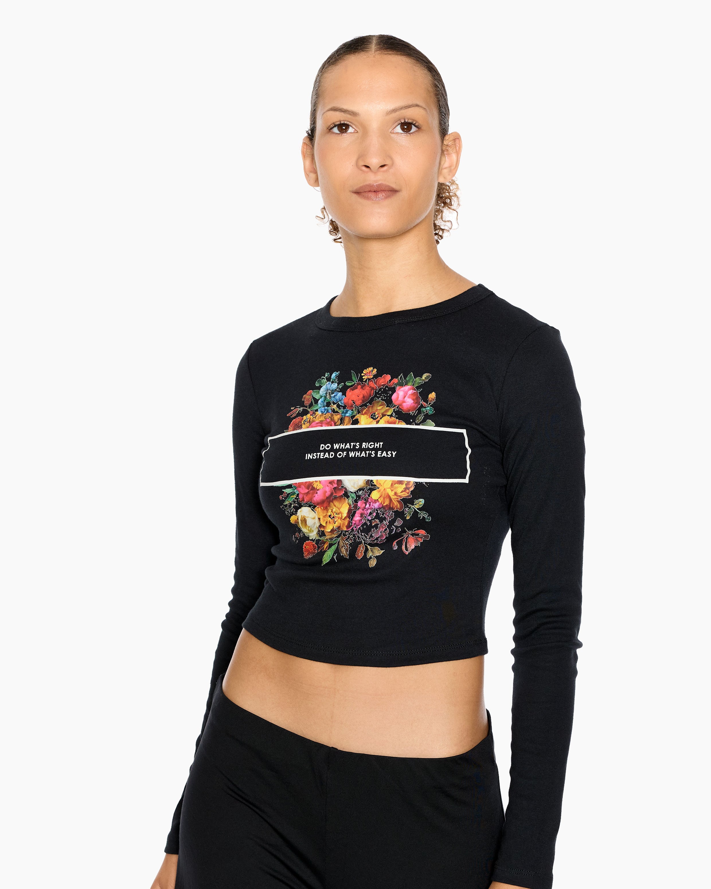 Woman wearing an Eleven27 black long-sleeve crop top with floral design and "Do What's Right Instead of What's Easy" text