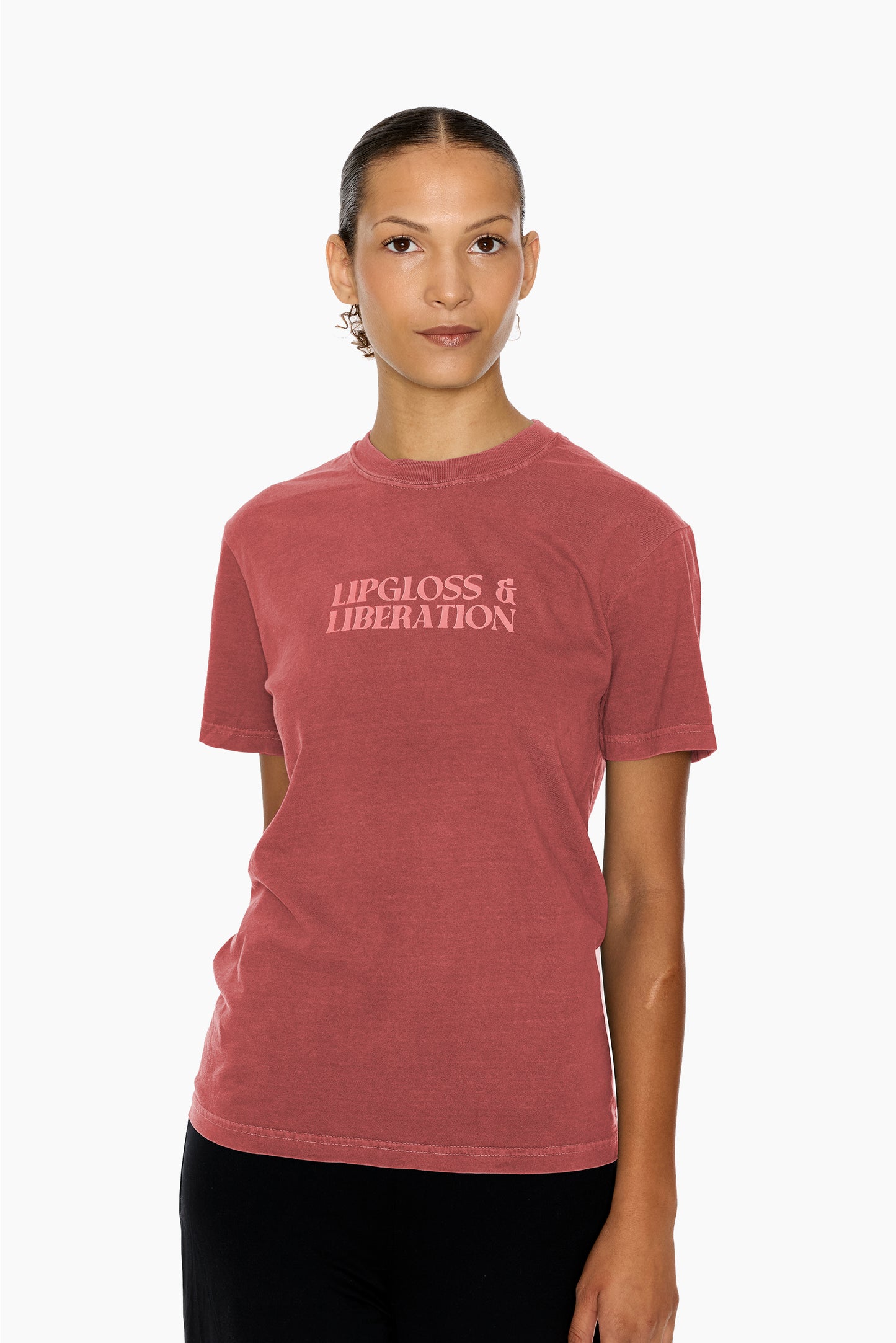 Person wearing a clay red t-shirt with 'Lipgloss & Liberation' text on a white background
