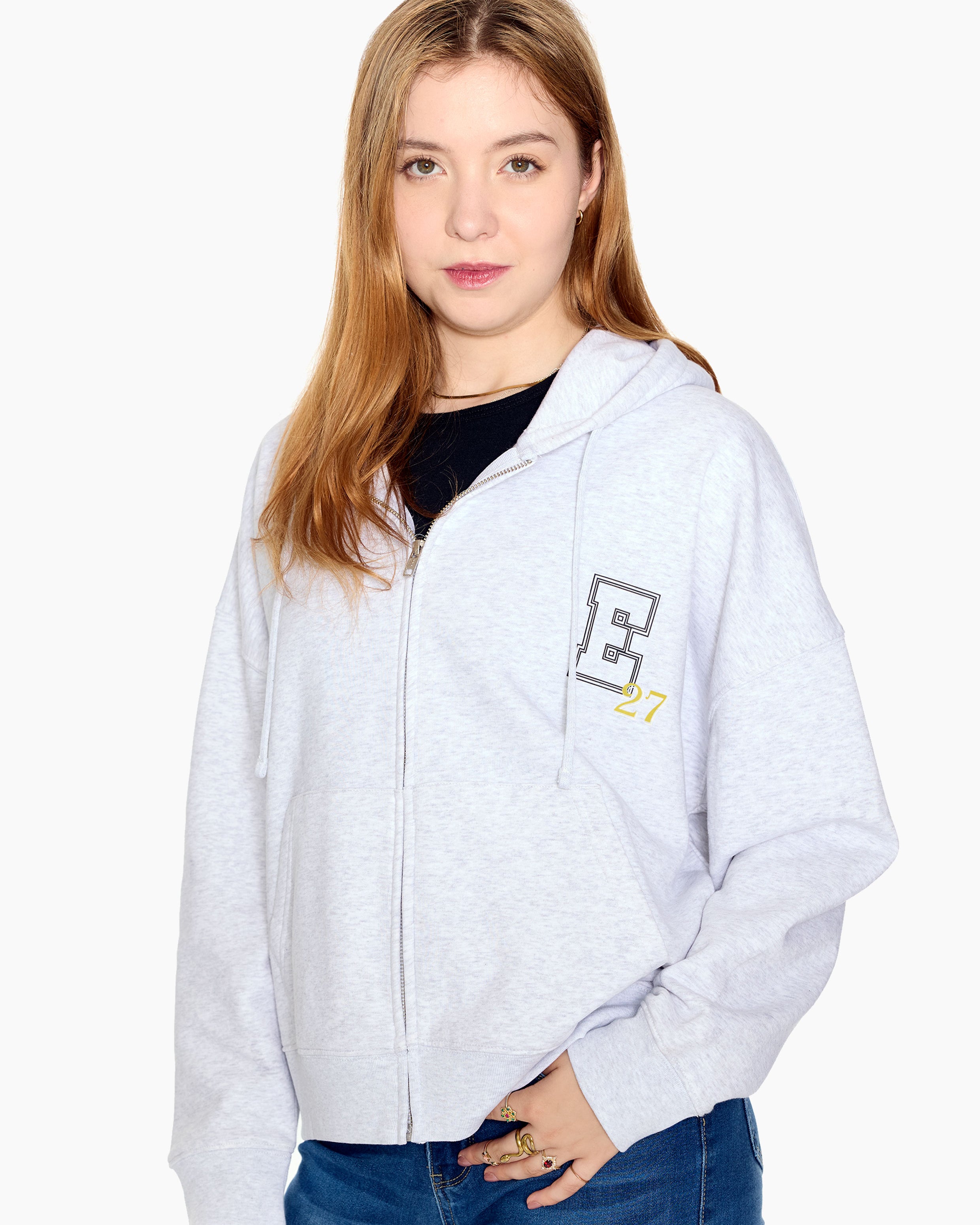 Woman wearing a light gray hoodie with a E27 logo on a white background