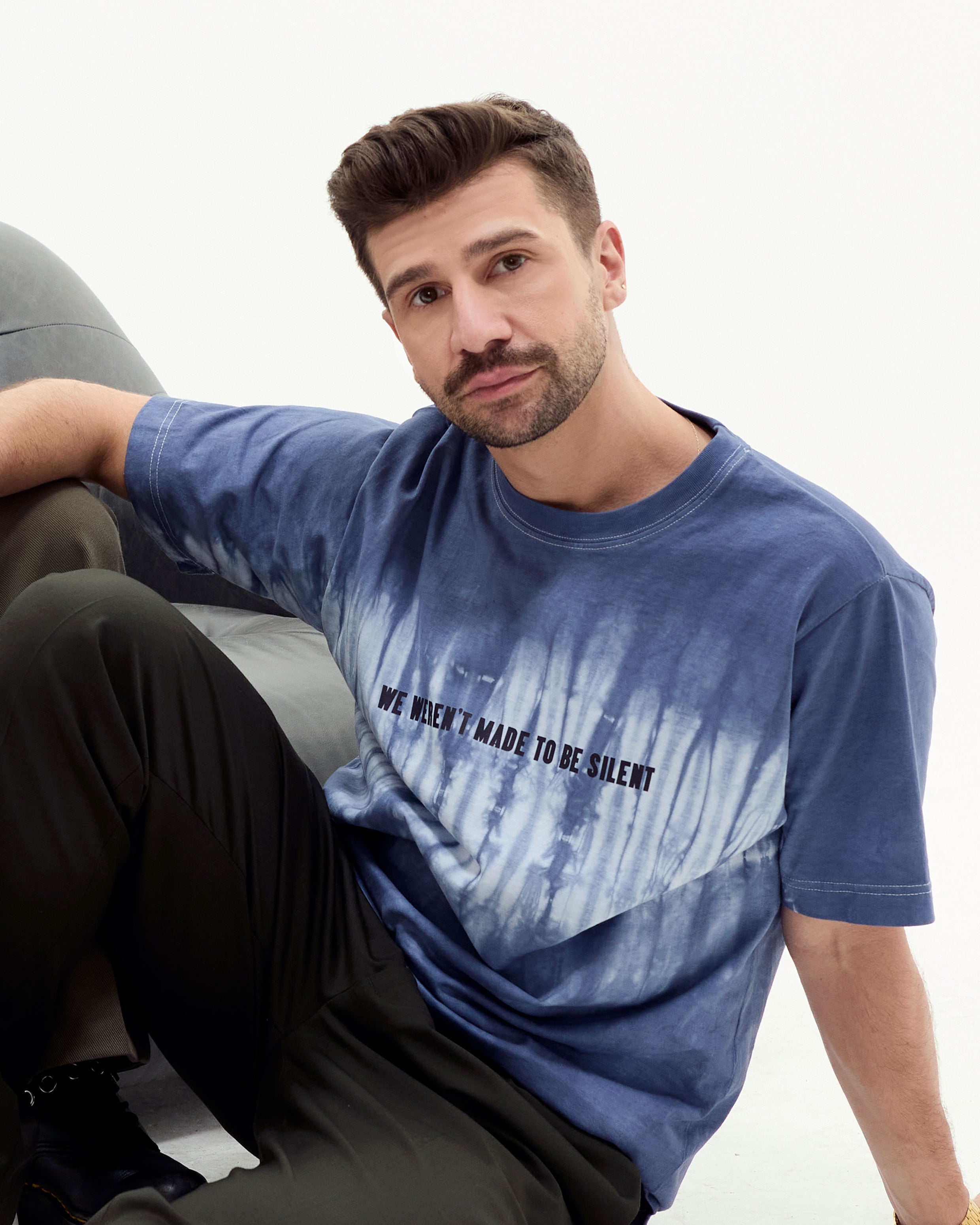 Model in navy and white tie dye tshirt with "We Weren't Meant To Be Silent" text. White background. Eleven27 brand