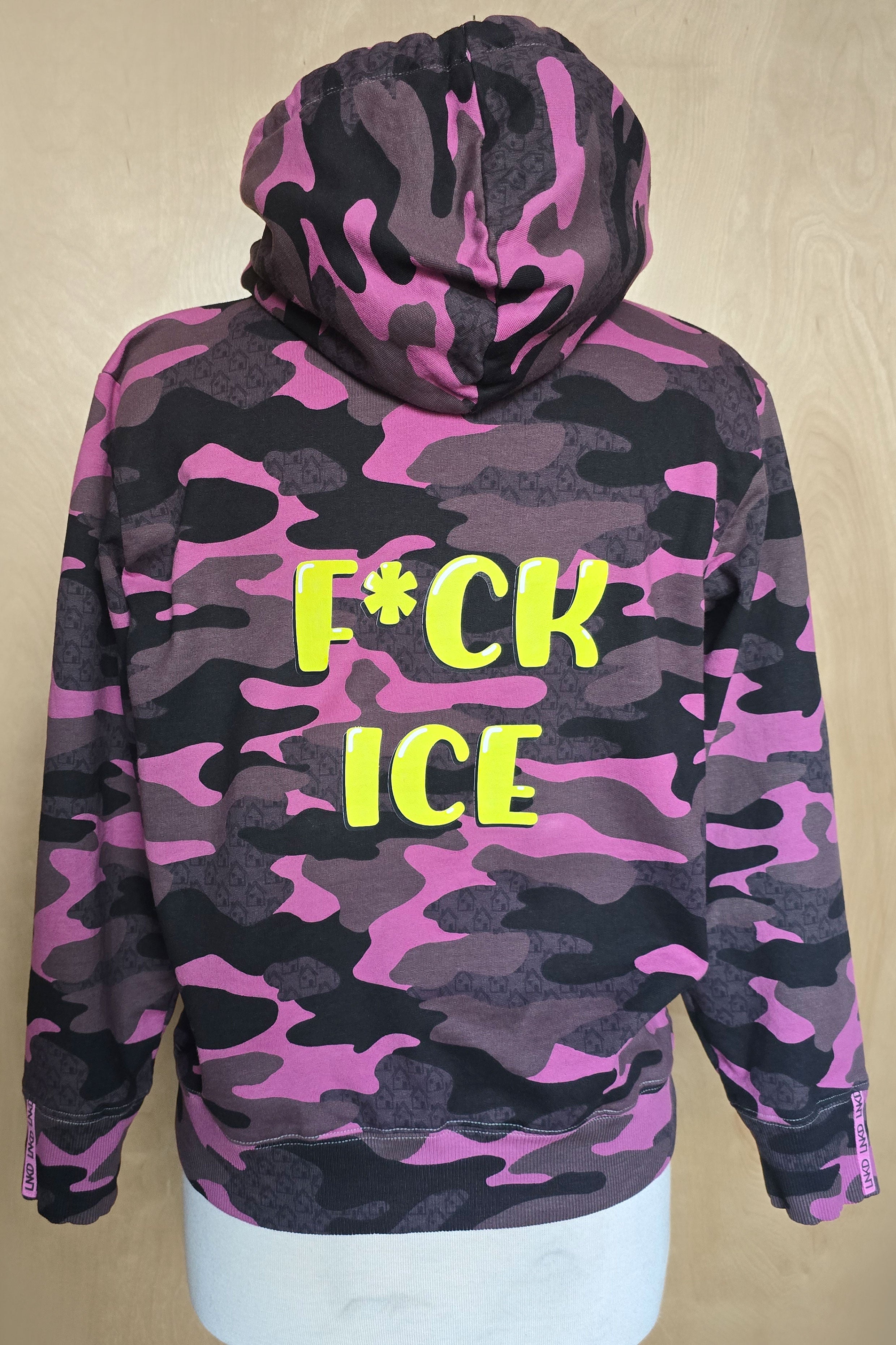 Camouflage hoodie with lime "F*ck ICE" text graphic on a beige background