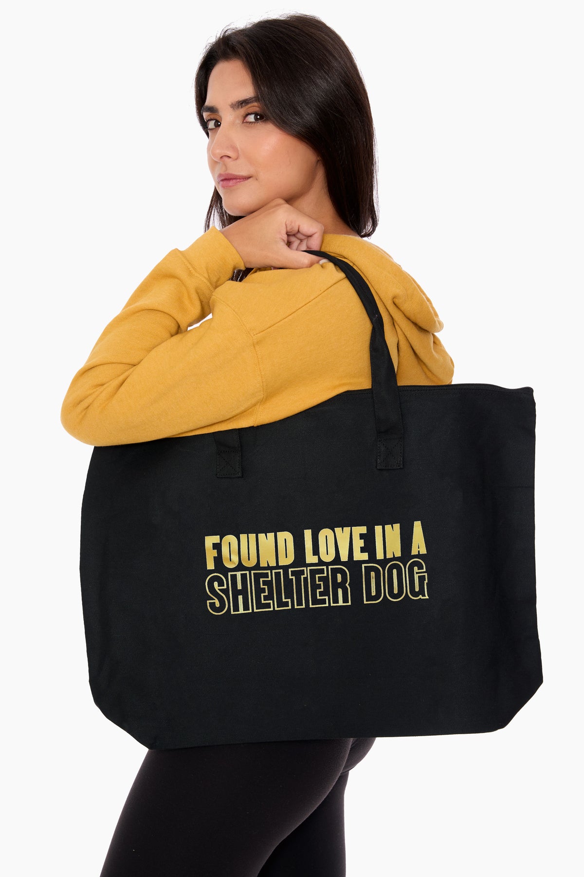 Woman holding a black tote bag with 'Found love in a shelter dog' text.