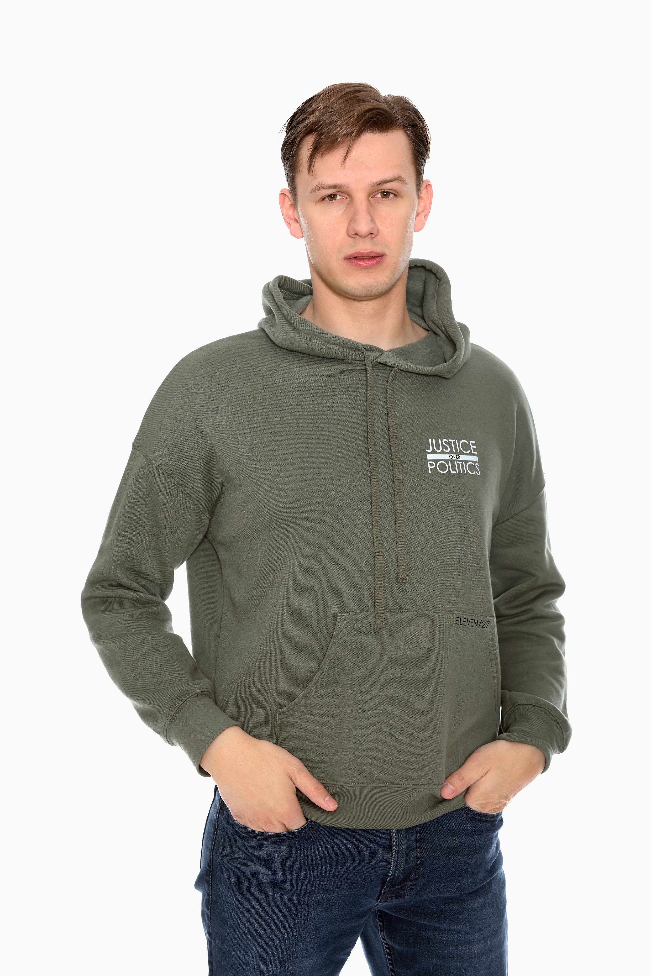 A male model wearing a green full-length hoodie with a "Justice Over Politics" graphic on the front and a logo on the back, featuring a front kangaroo pocket and drop shoulder design.