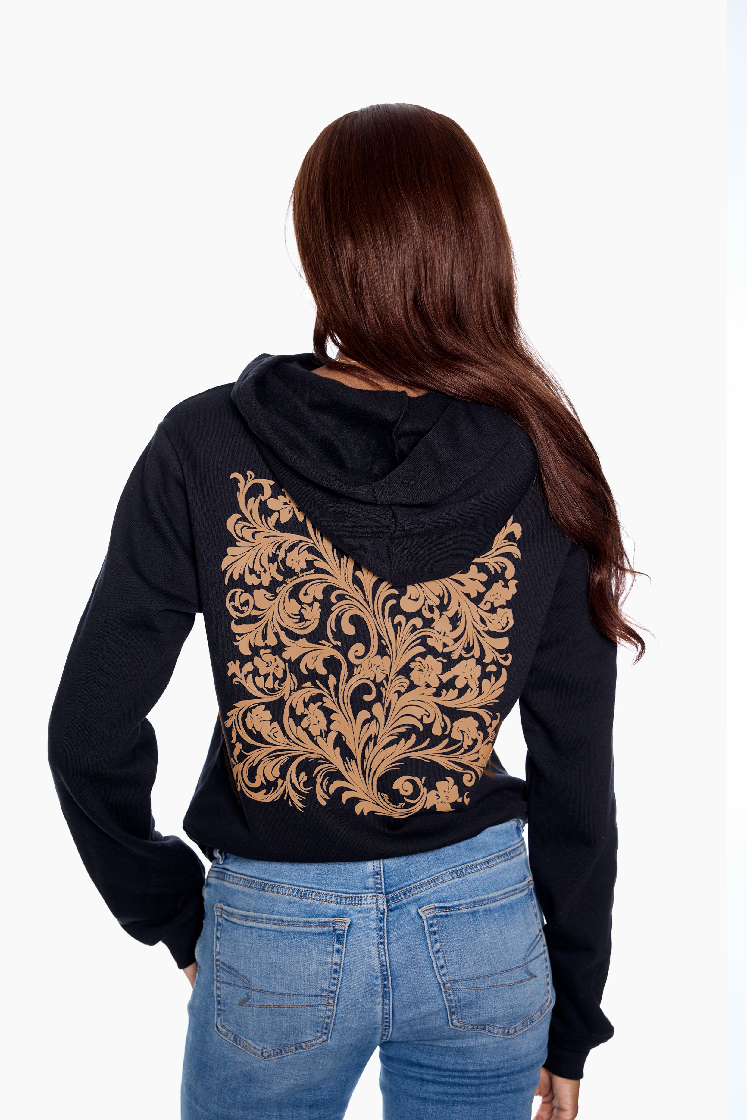 Person wearing a black hoodie with gold intricate design on the back, standing against a white background.