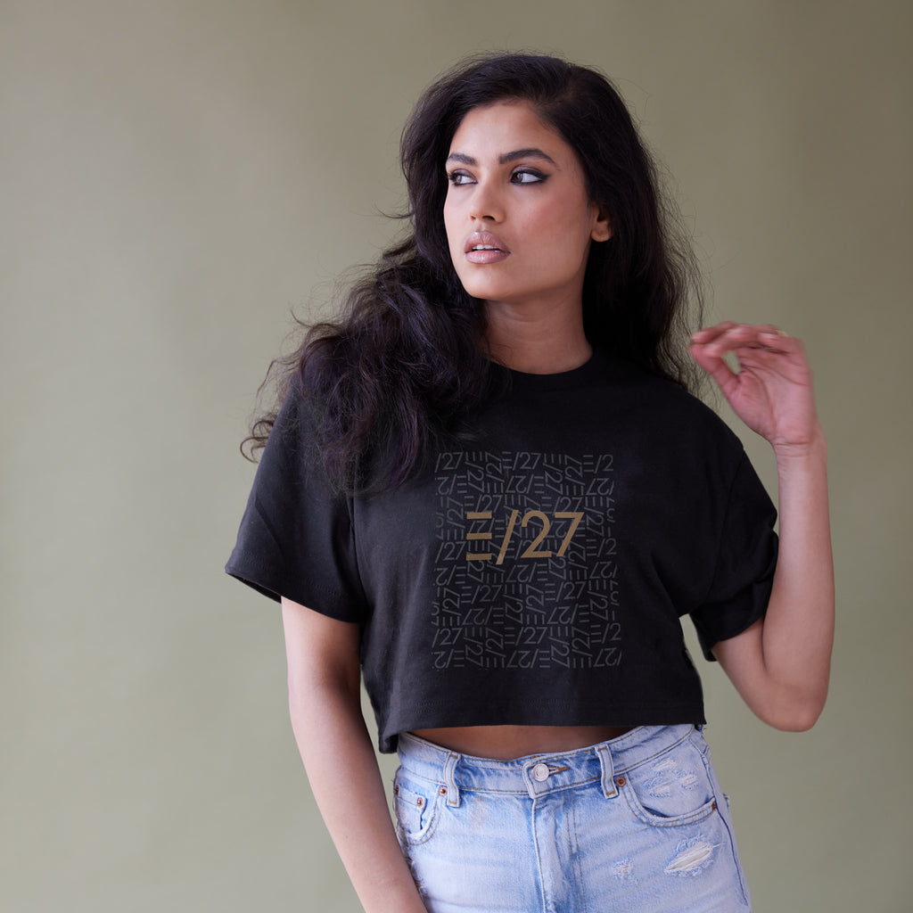 Exotic woman in a black cropped tshirt with E27 layered logo. Model is also wearing destructed jeans