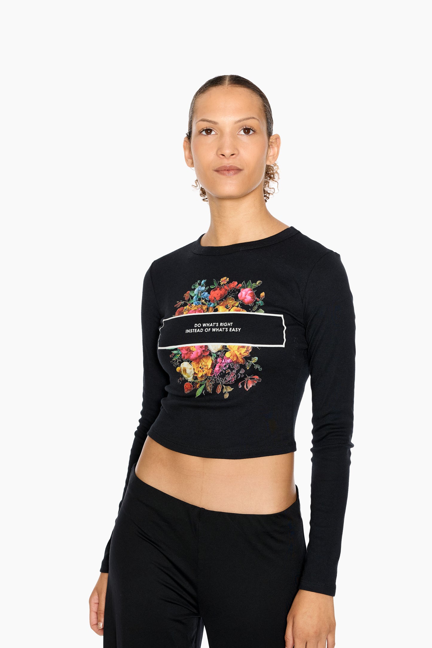 Woman wearing an Eleven27 black long-sleeve crop top with floral design and "Do What's Right Instead of What's Easy" text