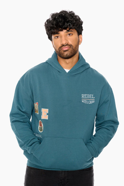 Man wearing a teal hoodie with patches and text on a white background
Eleven27 French Terry hooded sweatshirt with patch-style graphics on the front.