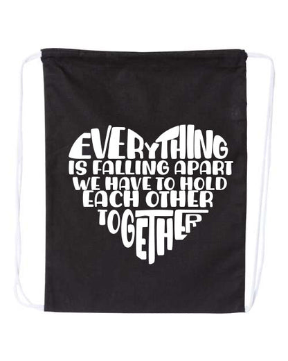 Black drawstring bag with EVerything Is Falling Apart We Have To Hold Each Other Together in white text on a white background