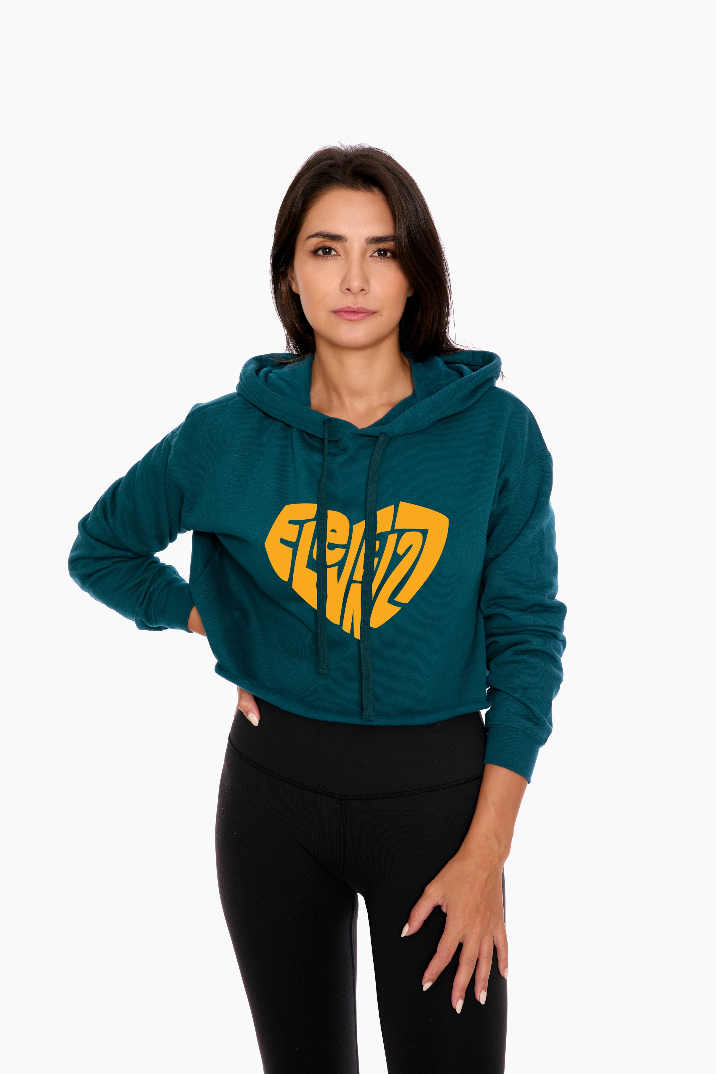 Woman in a teal cropped hoodie with a gold Eleven27 logo in the shape of a heart