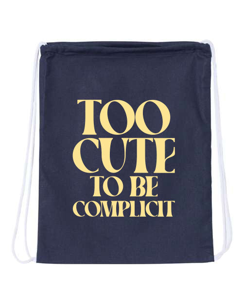 Navy drawstring bag with 'Too Cute to Be Complicit' text in gold on a white background